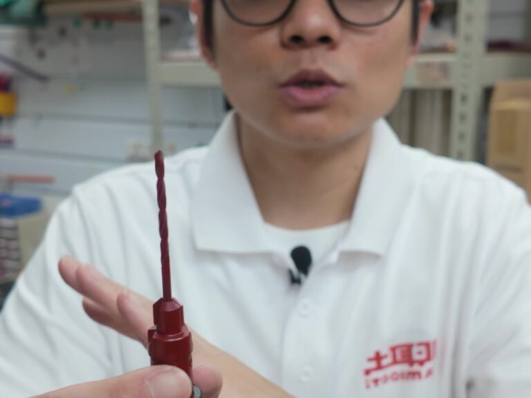手持整支木作鑽兼鎖，可見螺旋鑽身與下方紅色沉頭鑽刀頭